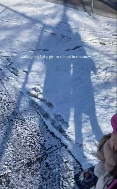 兩母女身穿厚實衣物在雪天手牽手上學,透過陽光照射下母女倆的影子也很溫馨