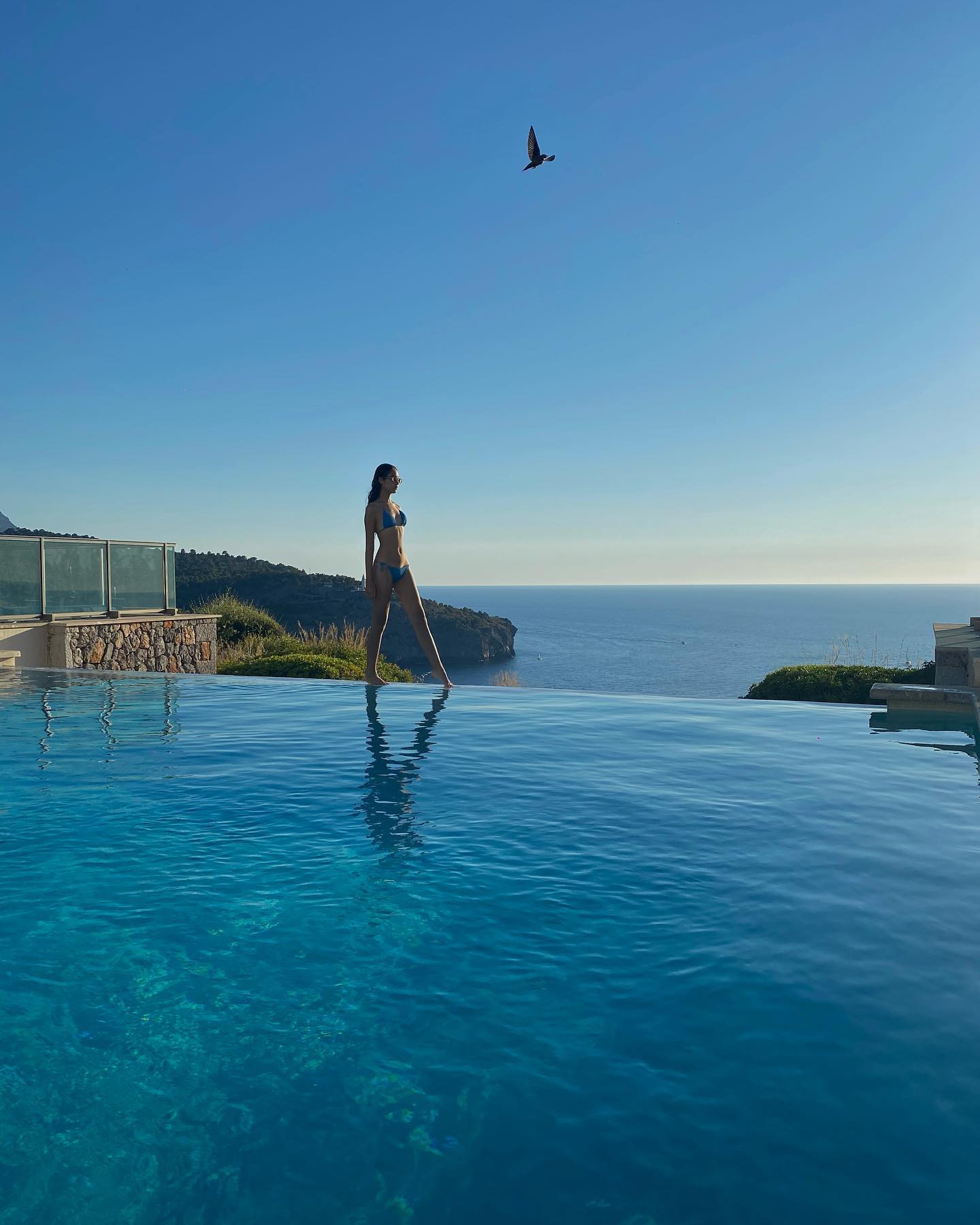 任晴佳在歐洲過暑假時分享身穿藍色比堅尼站在無邊際泳池的相片。
