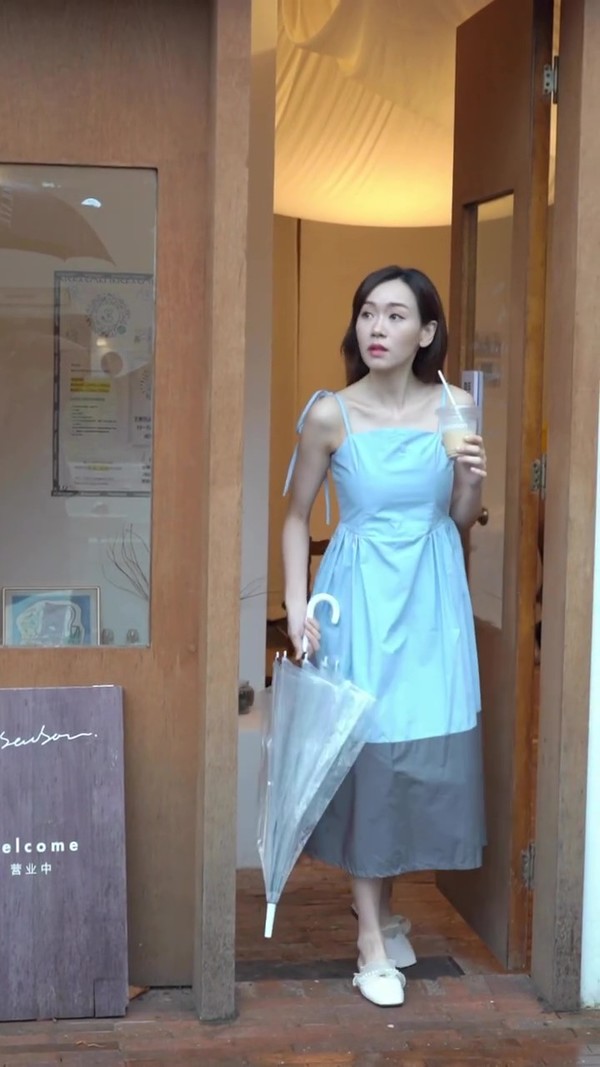 楊思琦身穿天藍色吊帶長裙,手拿著一杯飲品步出餐廳。