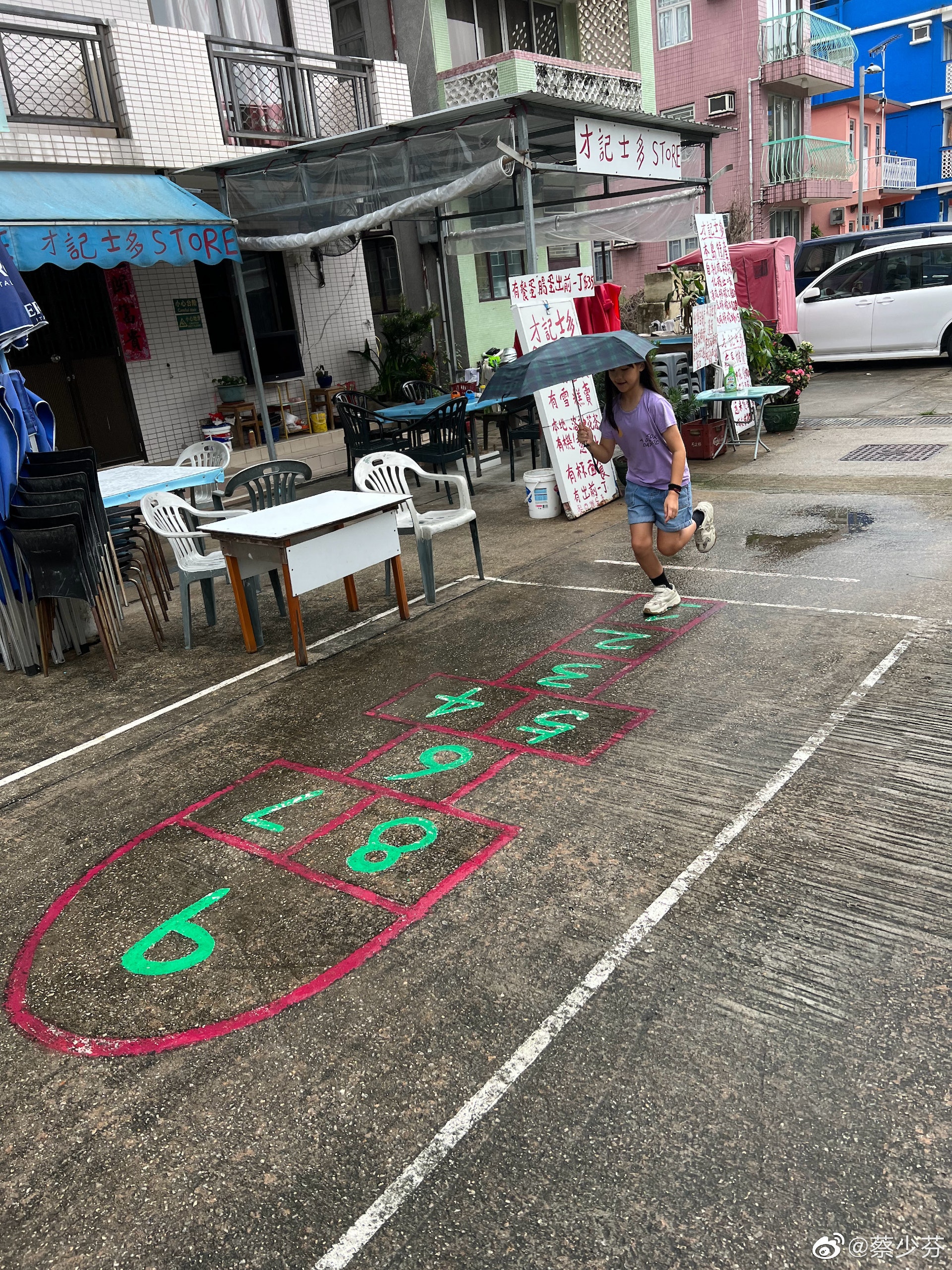 蔡少芬的9歲二女信兒在士多前玩跳飛機。