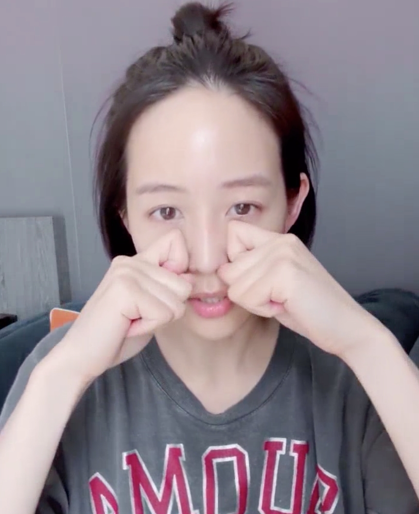 張鈞甯用雙手握拳使用指節按摩，從鼻翼兩側將蘋果肌由下往上推。