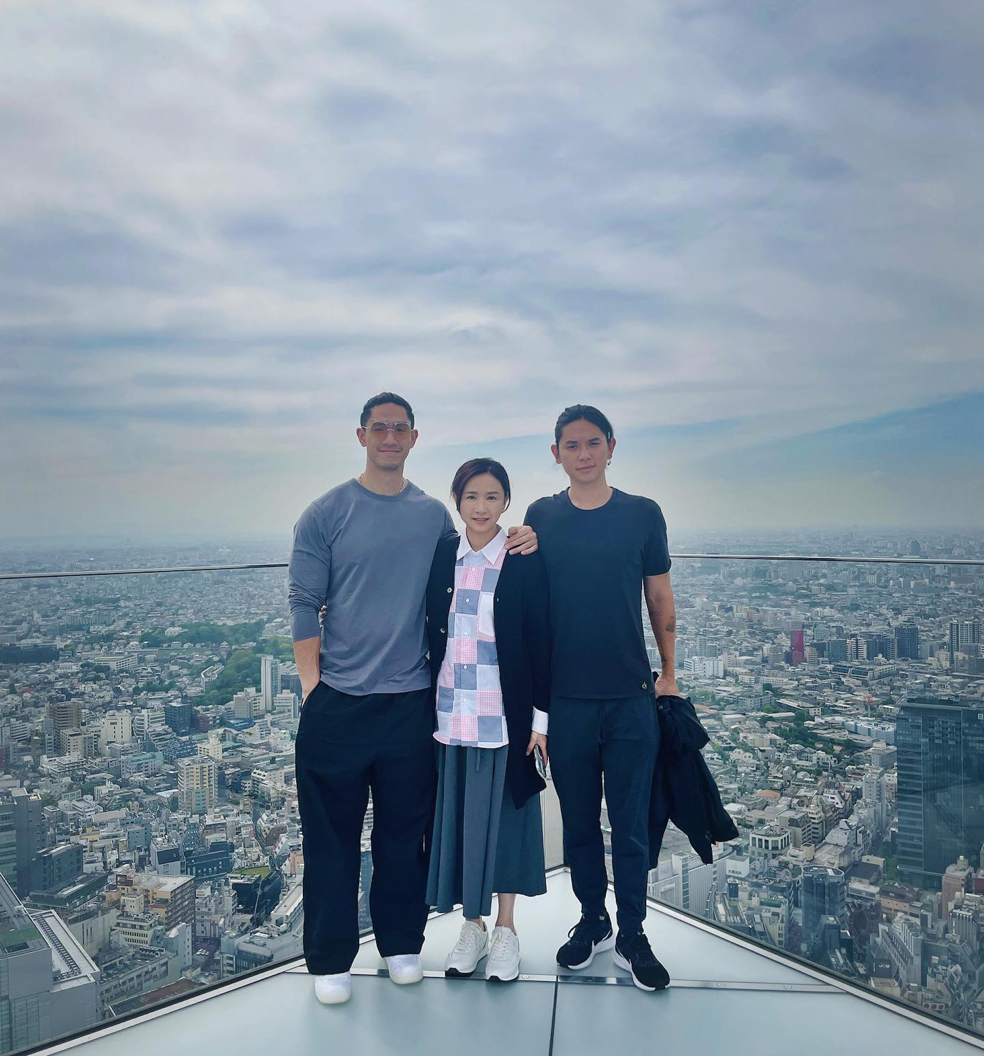 吳婉芳身穿格仔恤衫襯半身裙,站在兩子中間,三人同框完全不似母子。