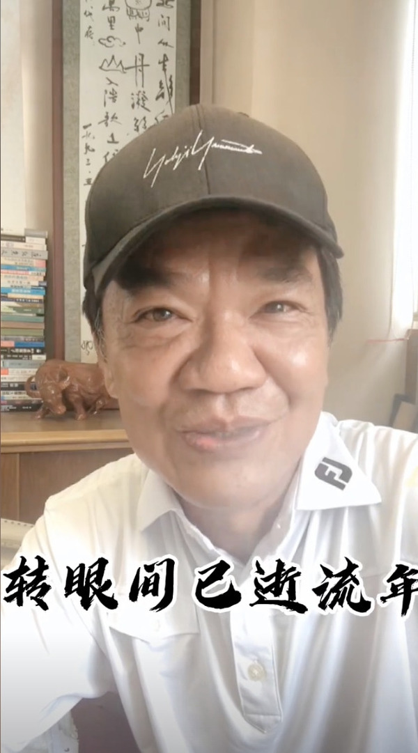 身後有黃霑送贈的《沉醉東風》字畫。