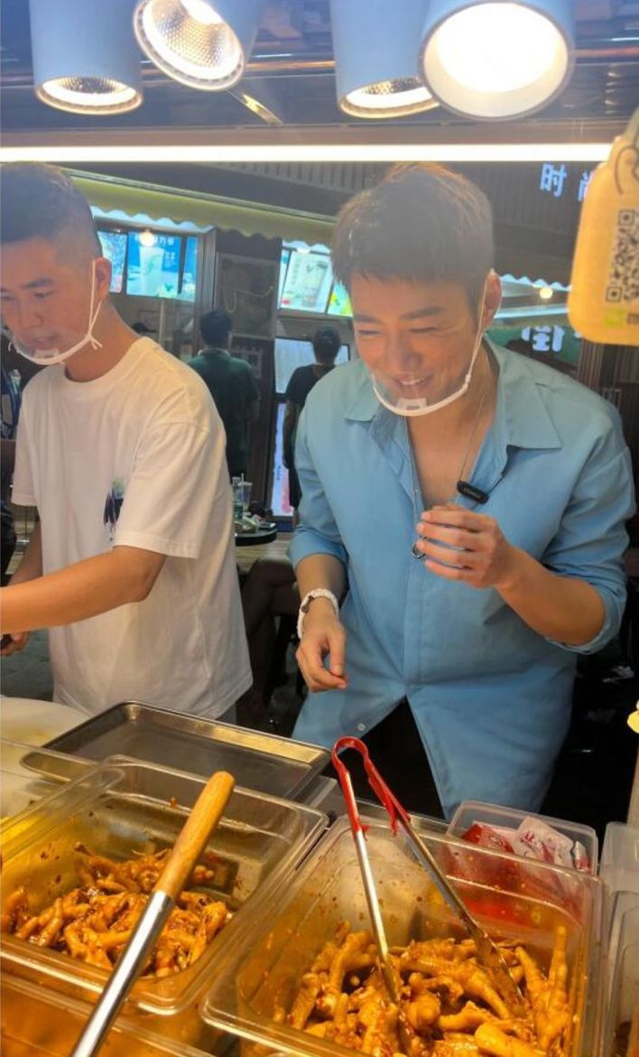 蔡淇俊身穿短袖襯衫、戴透明口罩，與拍檔努力工作。