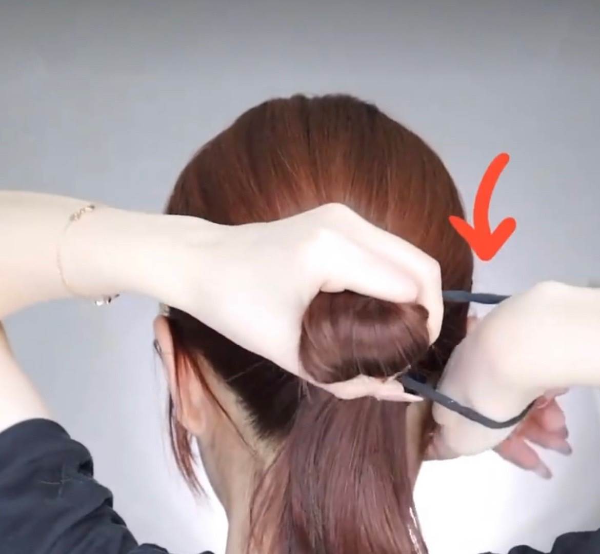 把髮圈套在右手上,將所有頭髮捏成一束,第1圈先照著綁低馬尾的方式。