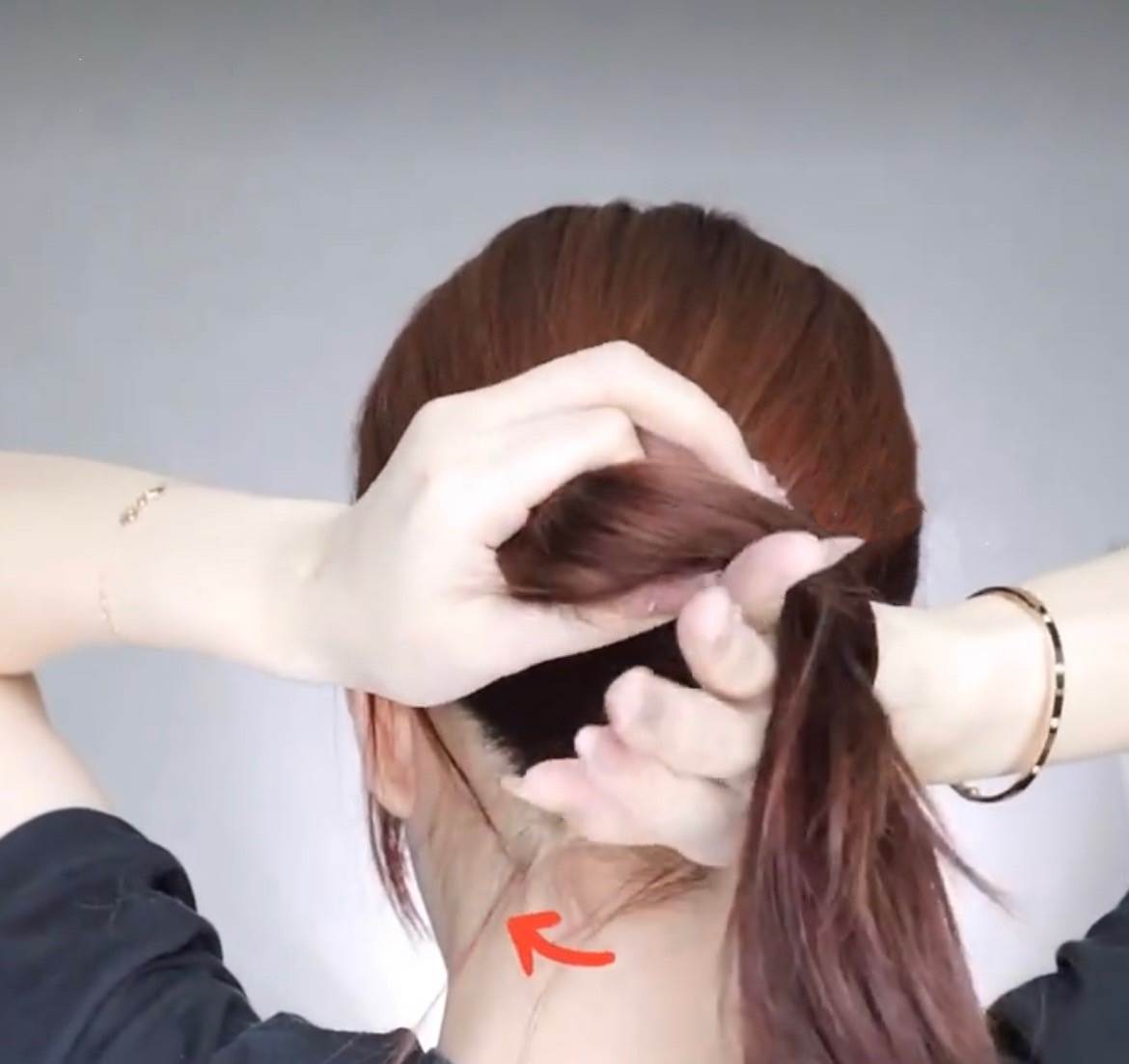 再來將手伸到髮尾貼近頭皮的位置,往上抓住剛剛預留的那1段頭髮。