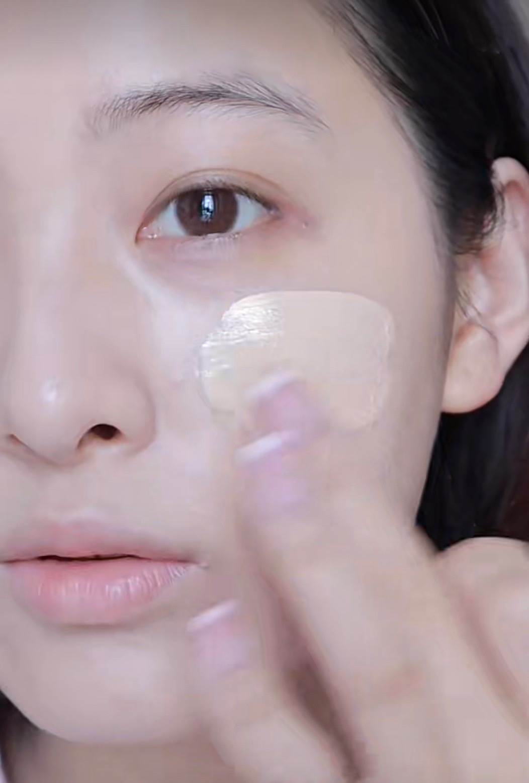 用手指沾取清透妝感的素顏霜或粉底液，均勻、輕薄地塗在臉上。