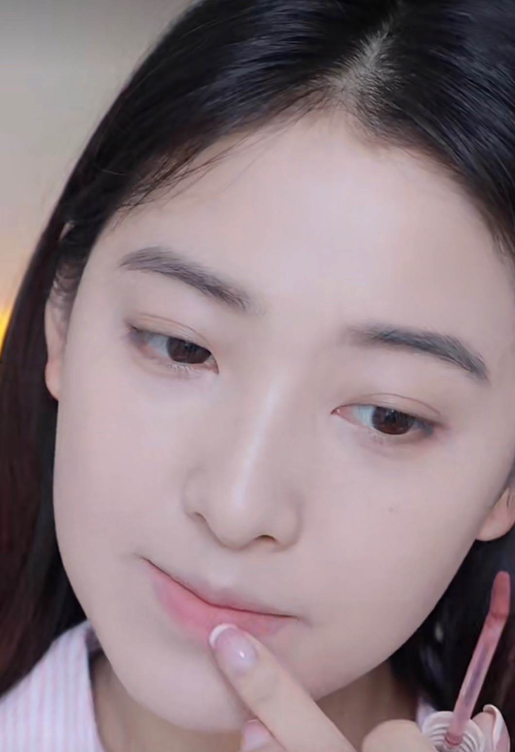 塗上裸粉色的唇膏，用手指將顏色暈染開。