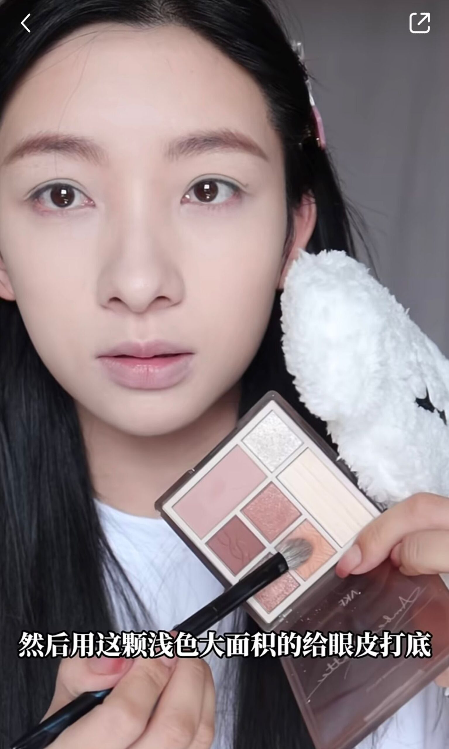 先用米白色眼影粉打底,再用大地色眼影,大面積地掃在眼皮上、下眼線位置。