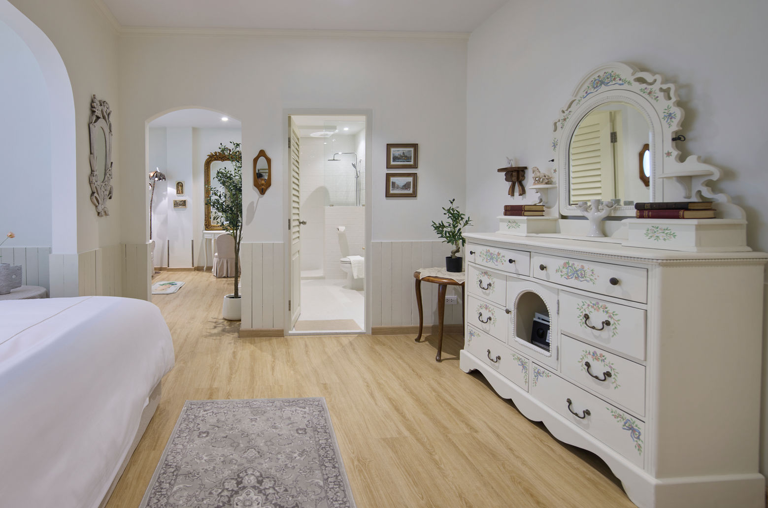 白色大床搭配精緻的雕花傢俱，還有米色窗簾和木質地板，讓房間看起來溫暖又奢華